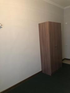 a room with a wooden cabinet and a white wall at Motel “Satti” in Shetpe