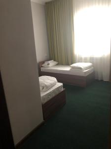 two beds in a room with a window at Motel “Satti” in Shetpe