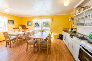 a kitchen with yellow walls and a table and chairs at Lydersen Rorbuer Budget Hostel & Private Apartments in Fredvang