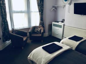 a bed room with a couch, chair and a television at Brierley Guesthouse in Weymouth