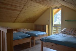 pokój na poddaszu z dwoma łóżkami i oknem w obiekcie Domki nad jeziorem w mieście Dąbrówno