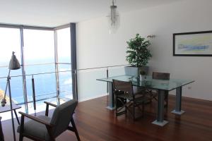 een eetkamer met een glazen tafel en stoelen bij Sea House Madeira in Garajau