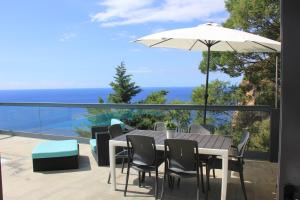 een tafel en stoelen en een parasol op een balkon bij Sea House Madeira in Garajau