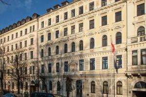 un grande edificio bianco con una bandiera davanti di Old City Park Apartment a Riga