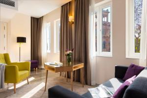 een woonkamer met een tafel en gele stoelen bij Torre Homenaje Historical Suites in Sevilla
