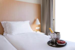 a tray with a bowl of fruit on a bed at Stay Hotel Faro Centro in Faro