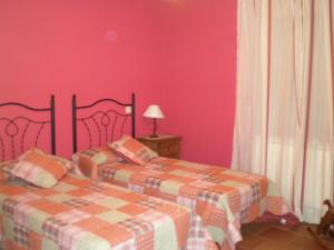 2 camas en una habitación con paredes rosas en Casa Rural Los Molinillos, en Caballar