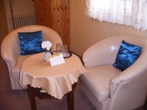 2 sillas y una mesa con una pequeña mesa con almohadas azules en Haus Sonnenschein, en Hahnenklee-Bockswiese
