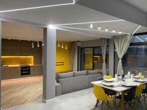 a dining room and kitchen with a table and yellow chairs at Brand new luxurios loft by the sea in Mamaia Nord