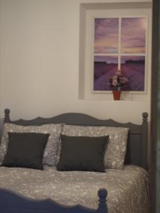 a bedroom with a bed with two pillows and a painting at Casa da Tia Dulce in Pataias