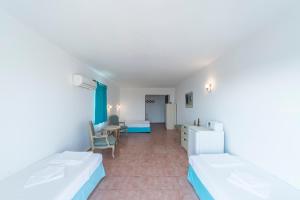a room with two beds and a desk and a table at Miramar Pansiyon in Kaş