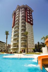 a hotel with a swimming pool in front of a building at Xperia Alanya Park Residence with large balcony and seaview & free airport shuttle service in Alanya