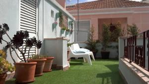 a patio with potted plants and a white chair at Casa Azul Hostel in Sintra