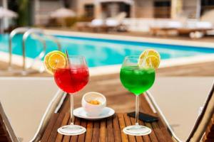 three wine glasses sitting on a table near a pool at ONOMO Hotel Abidjan in Abidjan