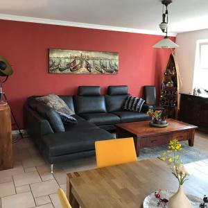 a living room with a black couch and a red wall at Raben Steinfeld Forststrasse Am Residence-Park in Raben Steinfeld