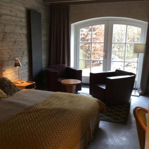 a bedroom with a bed and chairs and a large window at B&B bij Bedaf in Uden