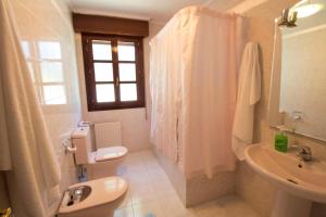 a white bathroom with a toilet and a sink at Casa Rural El FerJo in Colunga