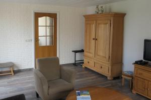 een woonkamer met een stoel en een kast bij Erve Eshuus Daarle in Daarle