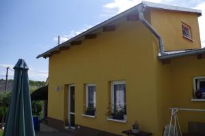een geel huis met een groene paraplu en een gebouw bij U Klárinky in Poštorná