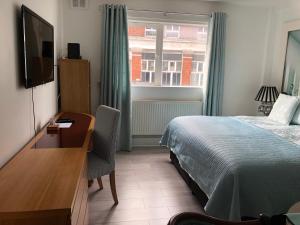 ロンドンにあるAffordable Lux and Cozy 1 bed flat in Chelseaのベッド、デスク、窓が備わるホテルルームです。