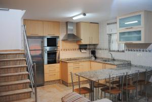 a kitchen with wooden cabinets and a kitchen island with chairs at Dúplex A Moa in O Pindo