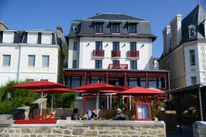 a restaurant with red umbrellas in front of a building at Hôtel Ar Iniz in Saint Malo