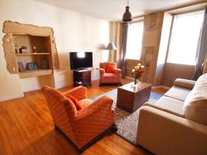 ein Wohnzimmer mit einem Sofa, Stühlen und einem TV in der Unterkunft Casco Histórico Apartamentos - Old Town Apartments in Santiago de Compostela