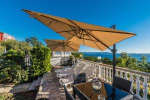 a patio with tables and chairs and an umbrella at Villa Mara in Crikvenica