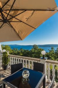 a table and chairs on a balcony with an umbrella at Villa Mara in Crikvenica