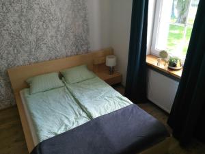 małe łóżko w sypialni z oknem w obiekcie Letnisko Rozwarowo w mieście Kamień Pomorski