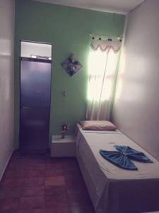 a small bedroom with a bed and a door at Hotel Ypê in Rio Verde