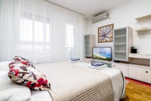 a white bedroom with a bed and a tv at Loko Savada in Belgrade