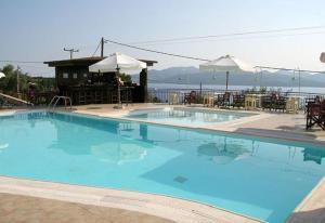a large blue swimming pool with tables and umbrellas at Anastasia Village in Nikiana