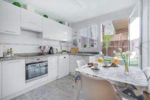 uma cozinha com armários brancos e uma mesa com cadeiras em Stylish Apartment em Villajoyosa