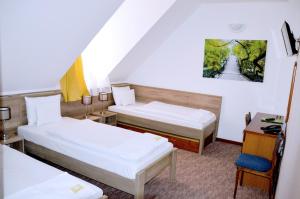 NagyhutaKőkapu Vadászkastély és Hotel & Apartments的有两张床和一张书桌的酒店房间