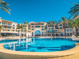 a large swimming pool with palm trees in front of a building at Apartment La Loma Mar Menor Golf Resort in Los Martínez