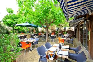 a restaurant with tables and chairs and a tree at Logis Hôtel Le Cygne in Le Bugue
