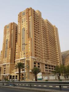 um grande edifício de apartamentos com palmeiras em frente em Altelal Apartment em Meca