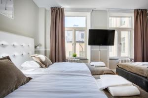 a bedroom with two beds and a flat screen tv at City Hotell Avenyn in Gothenburg