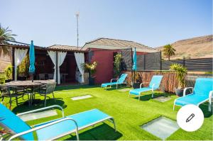 d'une terrasse avec des chaises bleues, une table et de la pelouse. dans l'établissement Casa Roque Aguayro, à Agüimes