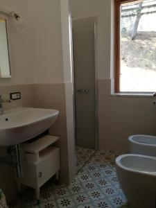 ein Bad mit einem Waschbecken, einem WC und einem Fenster in der Unterkunft Villetta Medusa in Copanello