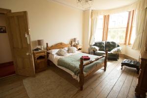 a bedroom with a bed and a chair and a window at Rosario in Marazion