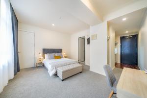 a white bedroom with a bed and a table and chairs at Studio 5E in Wellington