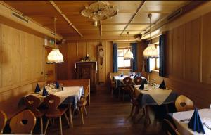 a dining room with tables and chairs and lights at Berggasthof Trattes in Valdaora