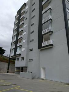a tall white building with balconies and a parking lot at Domus Angelis in Cachoeira Paulista