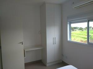 a white bedroom with a window and white cabinets at Domus Angelis in Cachoeira Paulista