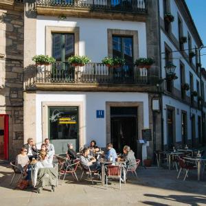 un grupo de personas sentadas en mesas frente a un edificio en Hotel Arco de Mazarelos en Santiago de Compostela