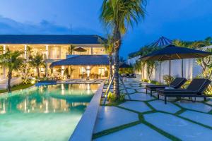 un complejo con una piscina con sillas y sombrillas en Villa Kusuma - Luxury Sea View 5 Bedroom Villa Close to Savaya, en Uluwatu