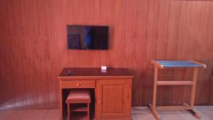 a desk with a chair and a television on a wall at Cafe Lava Hostel in Bromo
