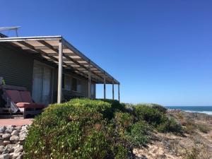 ein Haus am Strand mit dem Ozean im Hintergrund in der Unterkunft Private Beach Cottage At Ecostays in Greenough